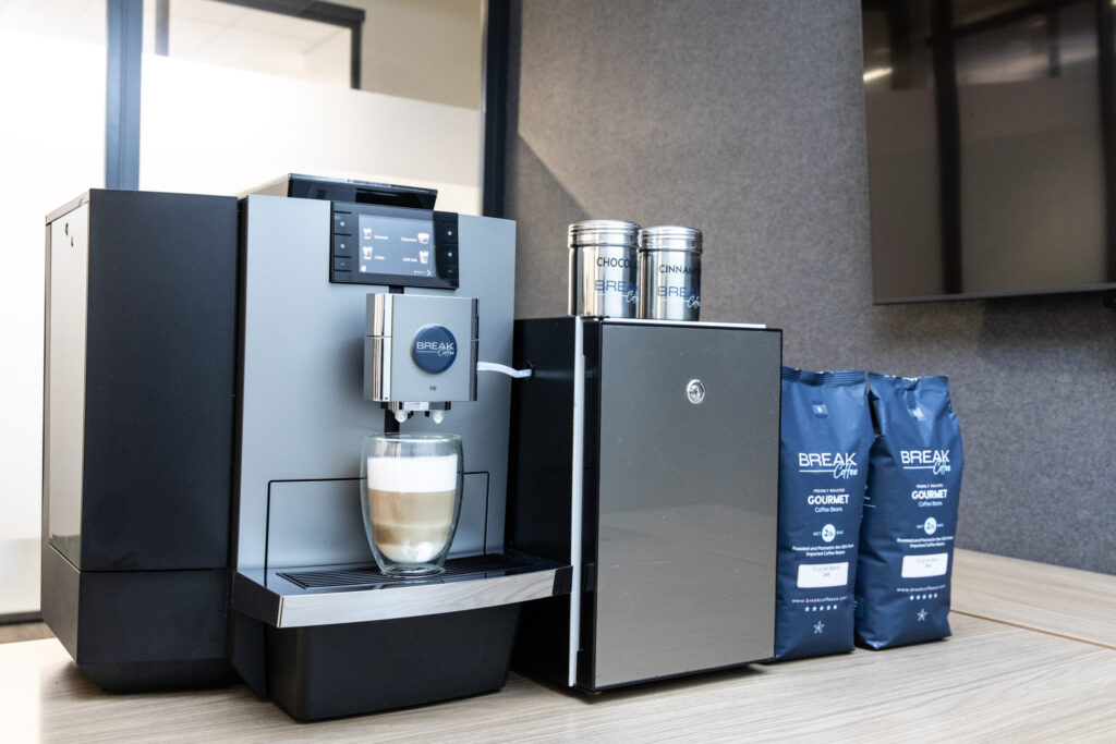 JURA X10 coffee machine beside its milk cooler and two bags of coffee beans