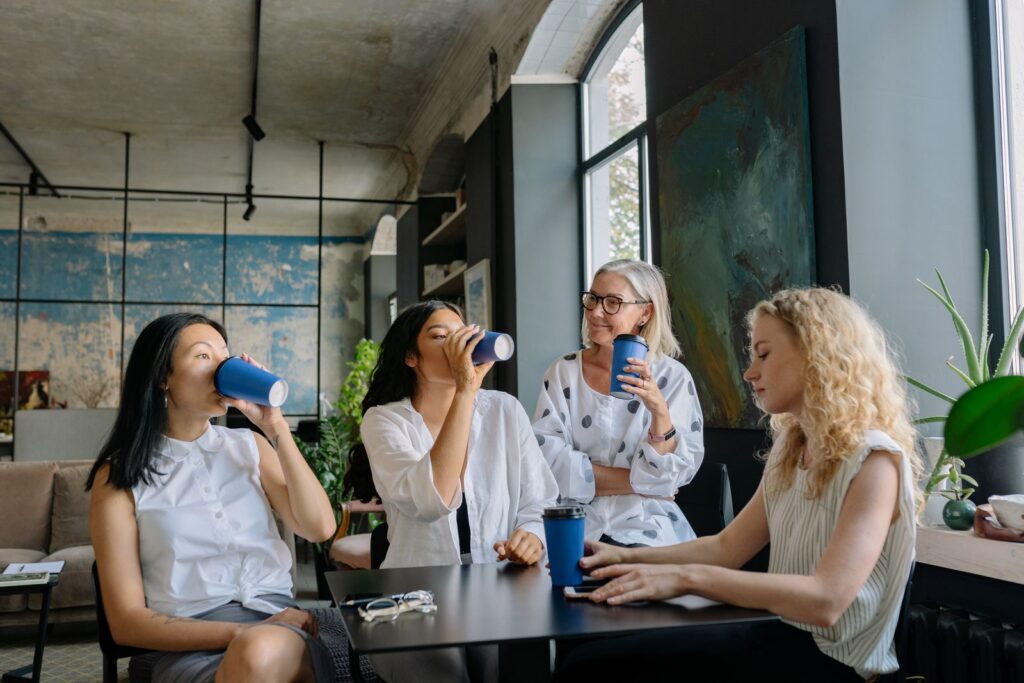 Four colleagues sharing a coffee break around a table in a bright office lounge